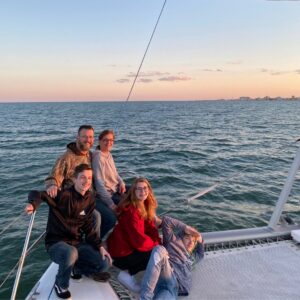 Family enjoying an ocean sailing trip aboard Alyosha catamaran with Ocean City skyline in the background
