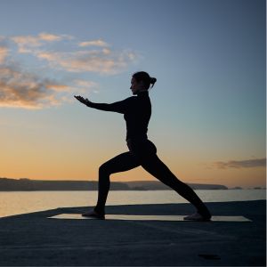 Yoga warrior pose silhouette at dawn over calm bay waters in Ocean City