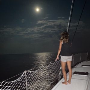 Woman enjoying moonlight sailing cruise on Alyosha catamaran trampoline netting