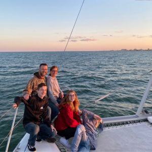 Family of Four sitting on the bow of 50 foot catamaran with the Atlantic Ocean in the background