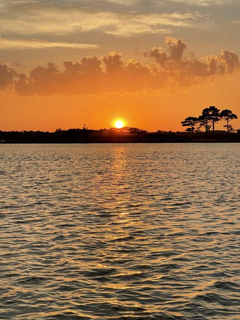 Sunset cruise Ocean City view of golden sun setting over Assateague Island marsh