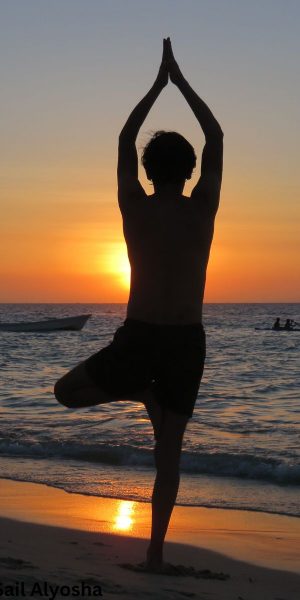 Person practicing tree pose yoga at sunset on Ocean City beach with ocean view