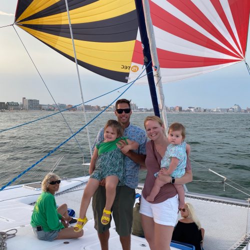 Family of five on a 50 foot catamaran in Ocean City, MD standing on the bow