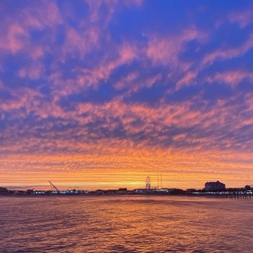 Sunset cruise Ocean City Maryland showing dramatic purple and orange sky over Sinepuxent Bay